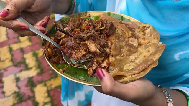 A girl holding a plate of Sukha mutton and paratha made with coconut oil. No face video