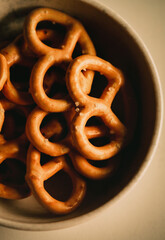 A photo of small, salted pretzels resting on a white plate. A delightful snack. Baked goods.
