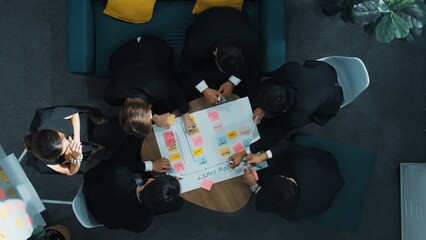 Close up of professional business team hands writing and putting sticky note on scrum task board....