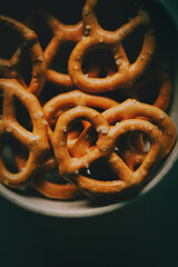 A photo of small, salted pretzels resting on a small, white saucer. Delicious snacks. Homemade cakes.