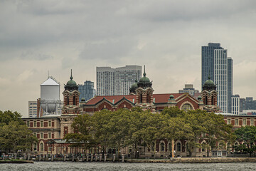 New York, NY, USA - August 4, 2023: Ellis Island National Museum of Immigration behind green...