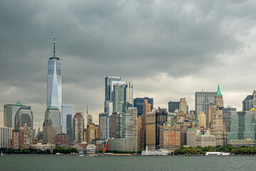 Obraz premium New York, NY, USA - August 4, 2023: Manhattan skyline N of Battery Park under gray menacing cloudscape, seen from the SW