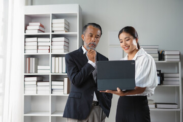 Businessman and businesswoman are standing in an office and having a discussion while looking at a digital tablet