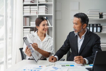 Two business people smiling and discussing about new project while working together in modern office