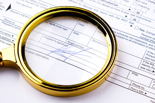 Signature on a document and a magnifying glass, concept of forensic handwriting examination of a signature
