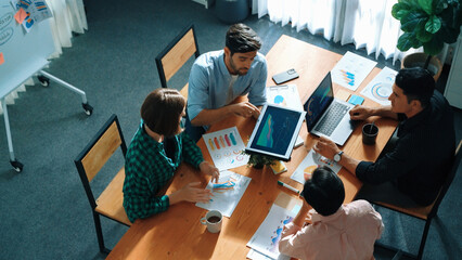 Top view of business people discuss idea while marketing team joining meeting. Manager pointing financial graph while colleagues talking to investor by using phone and brainstorm idea. Convocation.