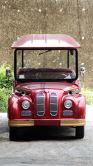 Vintage Red Tourist Car with Canopy Parked on Concrete Ground against Stone Wall Background