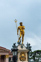 Obraz premium Batumi, Georgia, 07.30.2024: Golden statue of Poseidon, the Greek god of the sea, prominently displayed in Batumi, Georgia, against a clear sky backdrop
