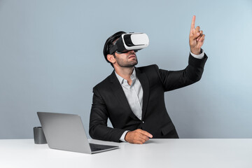Skilled business man looking at data analysis while sitting at table with laptop and wearing VR glasses. Project manager working by using virtual reality system or connecting at metaverse. Deviation.