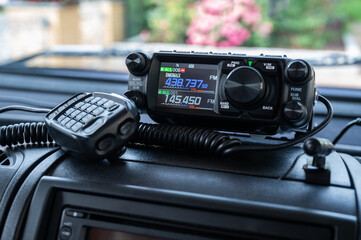 Mobile amateur radio transceiver with microphone for the 2m and 70cm band on a car dashboard