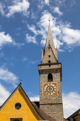Fototapeta premium Brunico (BZ), August 03, 2024. Bell tower of the Ursulinen Holy Saviour church in the historic city of Bruneck or Brunico, South Tyrol, Italy