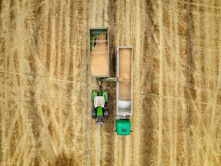 bird’s view of the tractor with grain cart loading wheat to the truck 