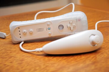 White gaming controller with nunchuck on a wooden table