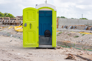 Green porta john restroom at a job site.