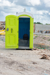 Green porta john restroom at a job site.
