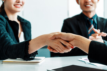 Business people agreement concept. Businessman and Asian businesswoman do handshake in the office. uds