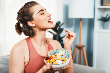 Healthy sporty and vegetarian woman in sportswear with a bowl of fruit and vegetable. Healthy cuisine nutrition and vegan lifestyle for fitness body physique at gaiety home concept.