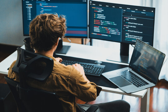 IT developer working online software development on pc monitors at modern home office on coding application screens, creating updated latest program firmware information version concept. Gusher.