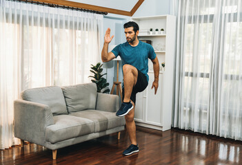 Fototapeta premium Athletic and sporty man running posture at home body workout exercise session for fit physique and healthy sport lifestyle at home. Gaiety home exercise workout training.