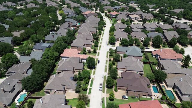 Residential street in upscale suburban neighborhood row of large mansion houses inground swimming pools, colorful shingle tile roofs, lush trees in Coppell, suburbs Dallas DFW metroplex, flyover