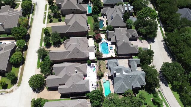 Modern inground and fiberglass swimming pools of large mansion houses in upscale suburban residential neighborhood, quite lush green street in Coppell, suburbs Dallas DFW metroplex, flyover