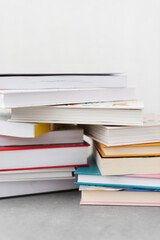 Stack of books with colorful bookbindings against white wall with copy space, book lover