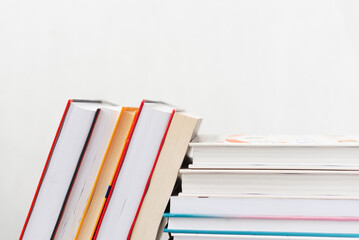 Stack of books with colorful bookbindings against white wall with copy space, book lover