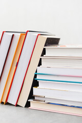 Stack of books with colorful bookbindings against white wall with copy space, book lover