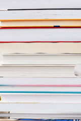 Stack of books with colorful bookbindings against white wall with copy space, book lover