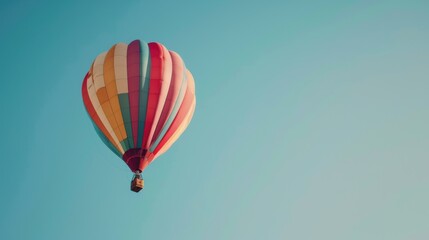 Obraz premium Colorful hot air balloon is flying in a bright blue sky, offering a sense of freedom and adventure
