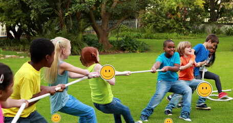 Image of falling icons over diverse school kids children pulling the rope