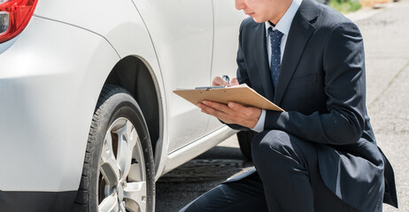 チェック表を使って車の査定・見積もりをするセールスマン・査定士の手元  © buritora