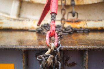 Steel chain and hook securing anchor, using to secure heavy object that transported on the trailer truck. Industrial safety equipment, close-up at the object.