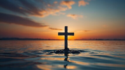 A striking cross stands prominently in calm waters as the sun sets on the horizon