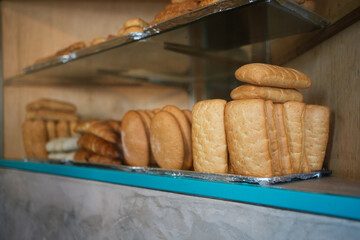 Various breads displayed on shelves in bakery shop.