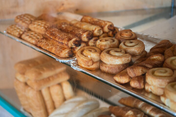 Close up of cinnamon rolls displayed on shelves in bakery store.