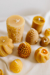 Handmade candles from natural beeswax in the shape of flowers, bears on a white background. Hobby. Handmade present. Gift. Artistic photo of beekeeping products in white room. Mockup. 