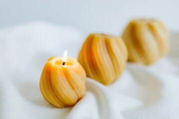 Handmade candles from natural beeswax in the shape of flowers, bears on a white background. Hobby. Handmade present. Gift. Artistic photo of beekeeping products in white room. Mockup. 