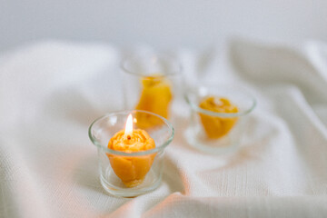Handmade candles from natural beeswax in the shape of flowers, bears on a white background. Hobby. Handmade present. Gift. Artistic photo of beekeeping products in white room. Mockup. 