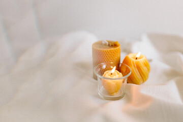 Handmade candles from natural beeswax in the shape of flowers, bears on a white background. Hobby. Handmade present. Gift. Artistic photo of beekeeping products in white room. Mockup. 