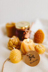 Organic honey in a glass jar and burning candles made of natural handmade wax on a white background. Beekeeping products. Small business. Farm.