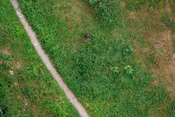 Aerial view of a small walkway in the midst of grassland, surrounded by scattered trash