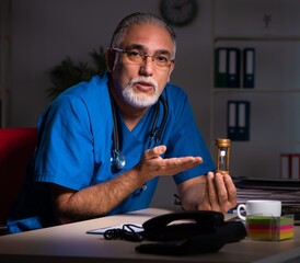 Aged male doctor in the hospital at night