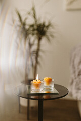 Burning candles made of natural handmade wax on a mirror tray in the dark in the house. Beekeeping products. Small business. Cozy interior with candles in the semi-darkness