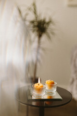 Burning candles made of natural handmade wax on a mirror tray in the dark in the house. Beekeeping products. Small business. Cozy interior with candles in the semi-darkness