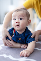 Asian newborn baby boy lying on the floor playing with colorful kid toys. Happy baby boy in kindergarten or daycare. Child playing with colorful educational toys in preschool. Kid play in playground.