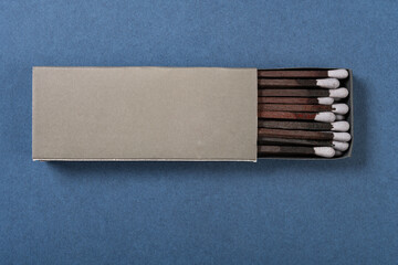 top view grey color matchbox and grey match sticks on a blue background