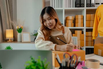 a beautiful female employee is packing clothing items into parcel box with great preparation...