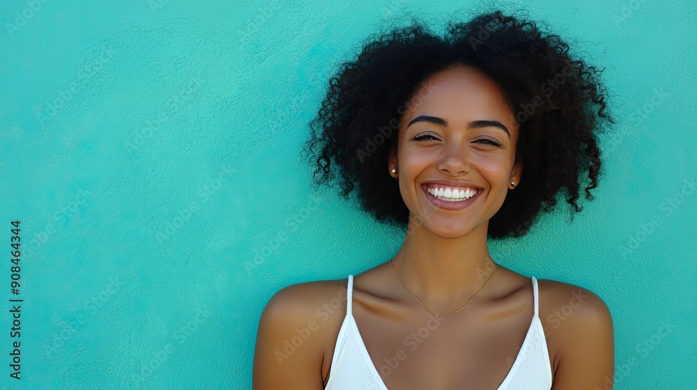 Wall mural Smiling woman in white casual attire, posed against an aqua blue-green backdrop, showcasing a cheerful and vibrant expression