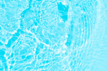 Blue water with ripples on the surface. Defocus blurred transparent blue colored clear calm water surface texture with splashes and bubbles. Water waves with shining pattern texture background.